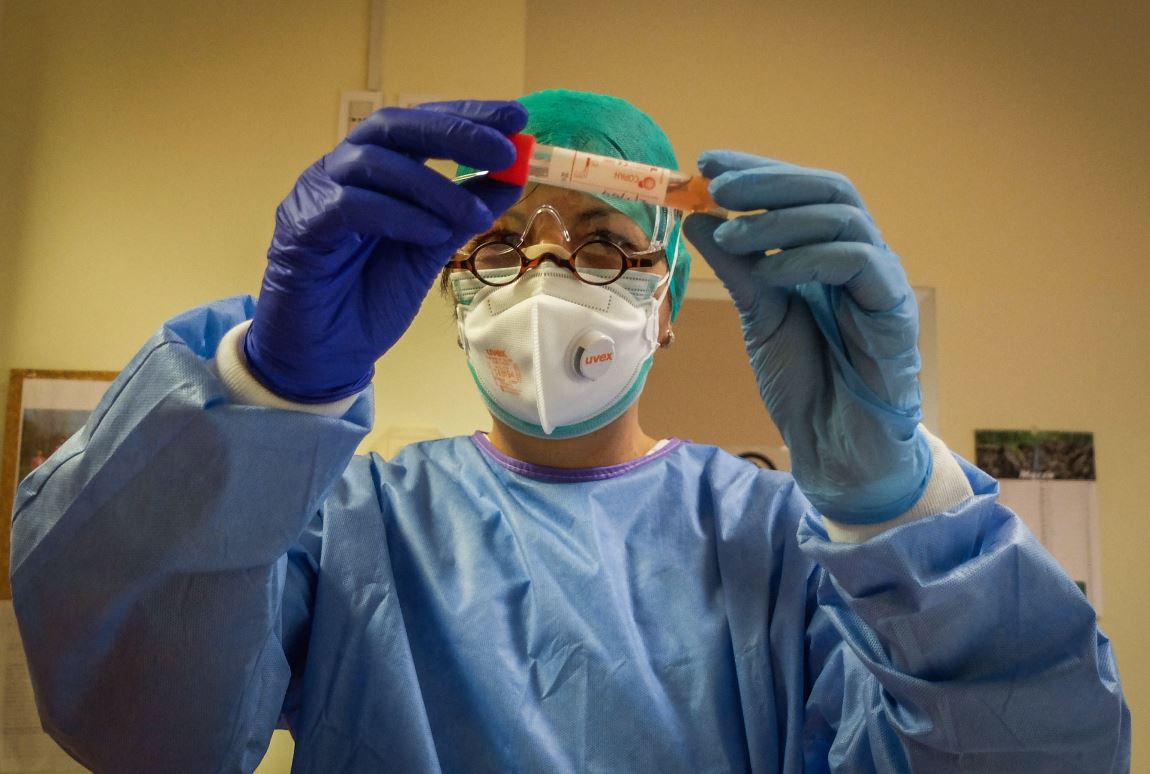 Un profesional de la salud inspecciona un vial que contiene una muestra de hisopo en un nuevo laboratorio de pruebas de coronavirus en la sala de enfermedades infecciosas del hospital de Cremona, Italia. (Foto Prensa Libre: EFE)