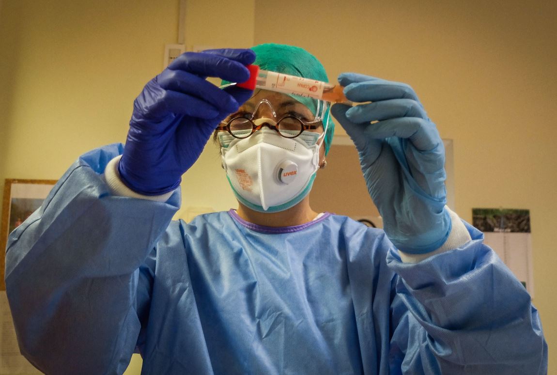 Un profesional de la salud inspecciona un vial que contiene una muestra de hisopo en un nuevo laboratorio de pruebas de coronavirus en la sala de enfermedades infecciosas del hospital de Cremona, Italia. (Foto Prensa Libre: EFE). 