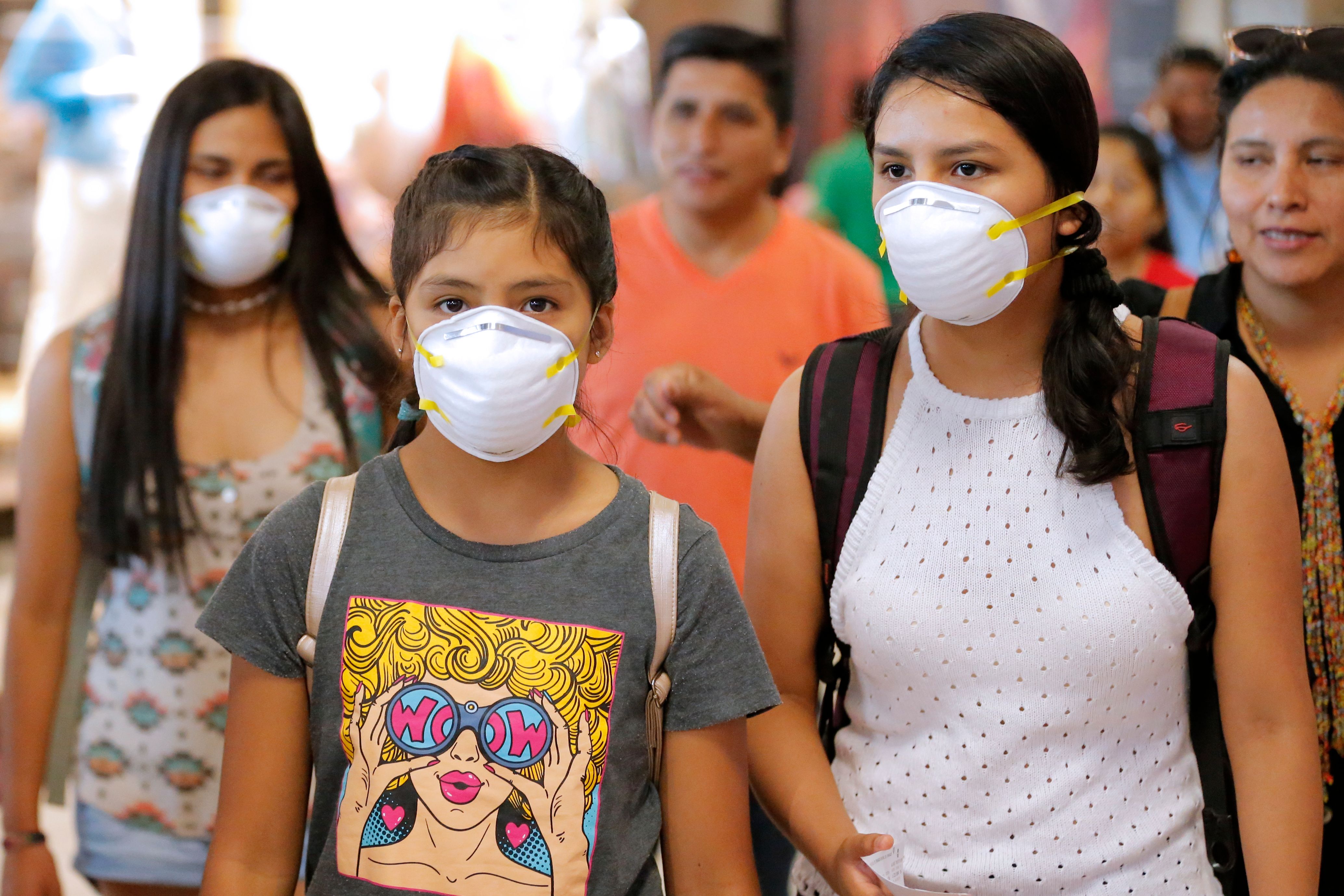 Passengers wear protective face masks as a precaution against the spread of the new Coronavirus, COVID-19, at Jorge Chavez International Airport, in Lima, on March 6, 2020. - Peruvian Government confirmed its first case of Coronavirus. President Martin Vizcarra reported that it is a 25-year-old male patient, who arrived from a trip to Spain, France and the Czech Republic. (Photo by Luka GONZALES / AFP)