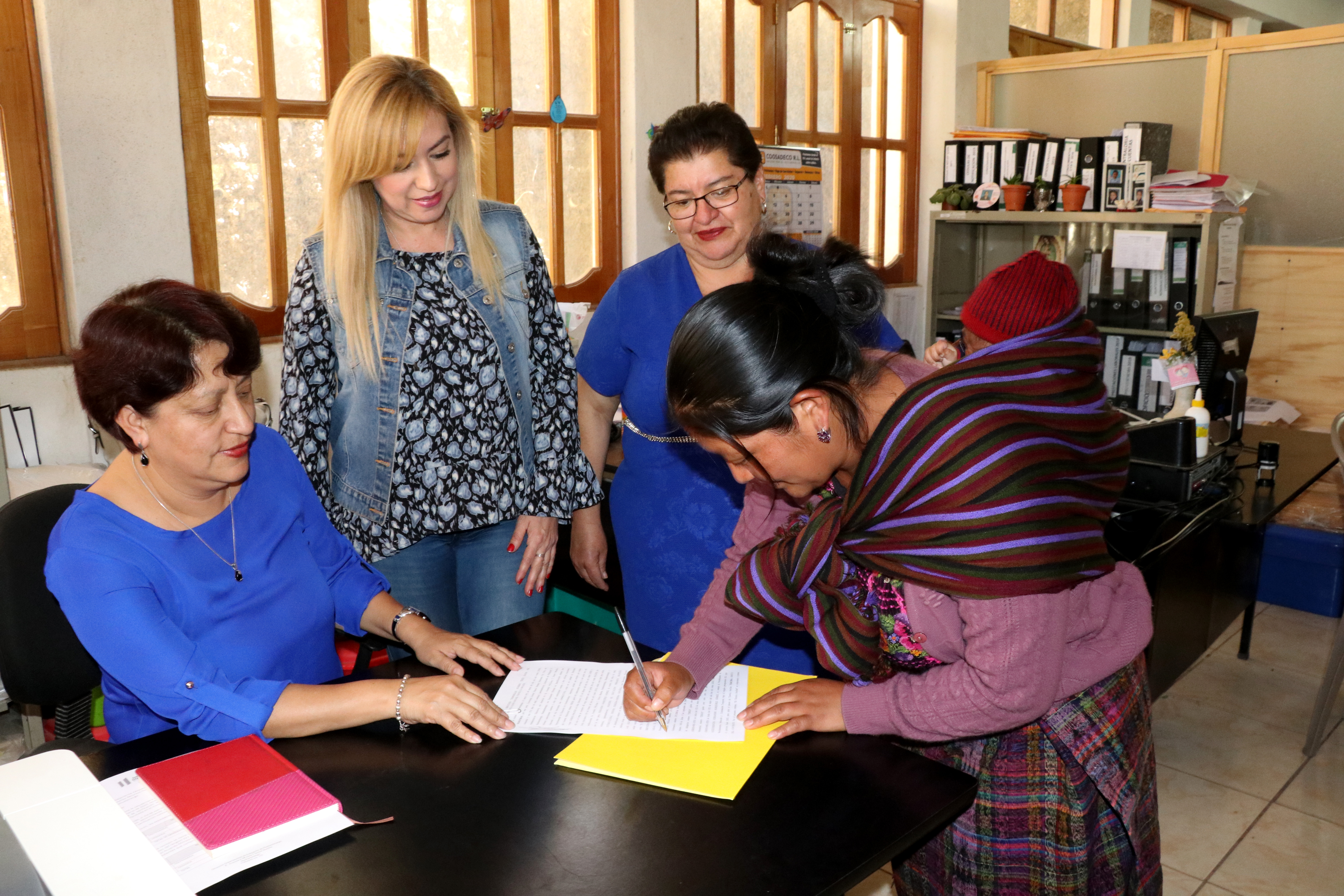 María Lucas Lucas con su bebé cargado en la espalda firma su contrato en la Dirección Departamental de Educación de Huehuetenango. (Foto Prensa Libre: Mike Castillo)