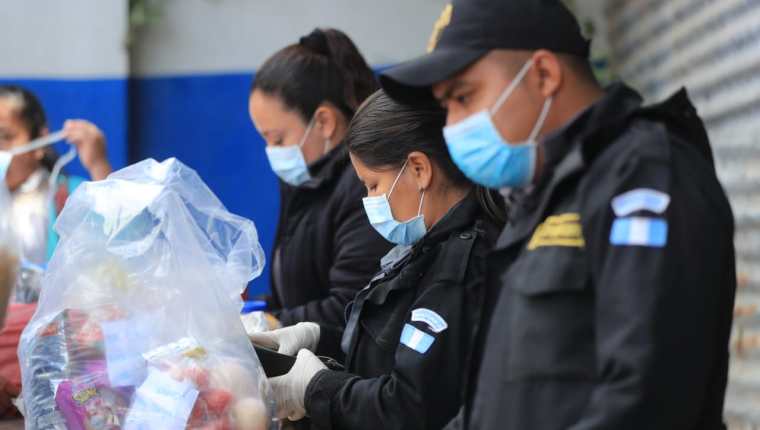 Custodios del Sistema Penitenciario revisan con guantes y mascarilla una bolsa con alimentos en el Centro Preventivo para Varones, en la zona 18.   (Foto Prensa Libre: Juan Diego González)  