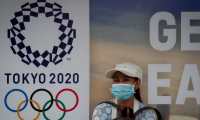 -FOTODELDÍA- ZSN01. BANGKOK (TAILANDIA), 24/03/2020.- Una mujer con una máscara sanitaria aguarda la llegada del autobús frente a un cartel de los Juegos Olímpicos de Tokio 2020, este martes en Bangkok (Tailandia). El Comité Olímpico Internacional (COI) cedió hoy finalmente a las presiones de federaciones y gobiernos y confirmó en un comunicado que los Juegos Olímpicos de Tokio se posponen "hasta el verano del año 2021, como muy tarde" a causa de la pandemia de coronavirus responsable del COVID-19. EFE/DIEGO AZUBEL