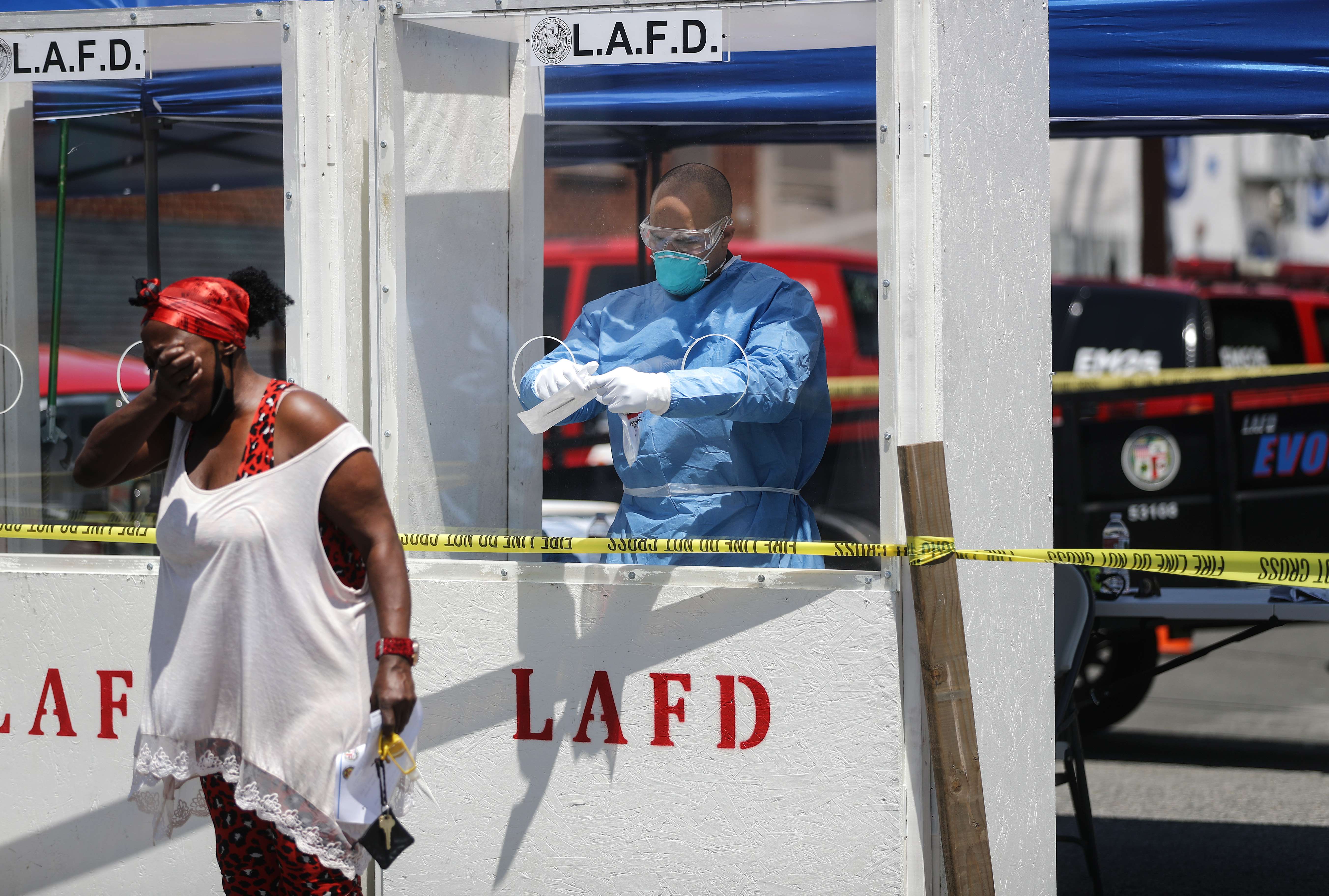 Un miembro del Departamento de Bomberos de Los Ángeles que usa equipo de protección personal (PPE) en Skid Row, en medio de la pandemia de coronavirus, le pide a una mujer que tosa en su brazo como parte de la prueba de covid-19, el 21 de abril de 2020 en Los Ángeles, California. (Foto Prensa Libre: AFP).