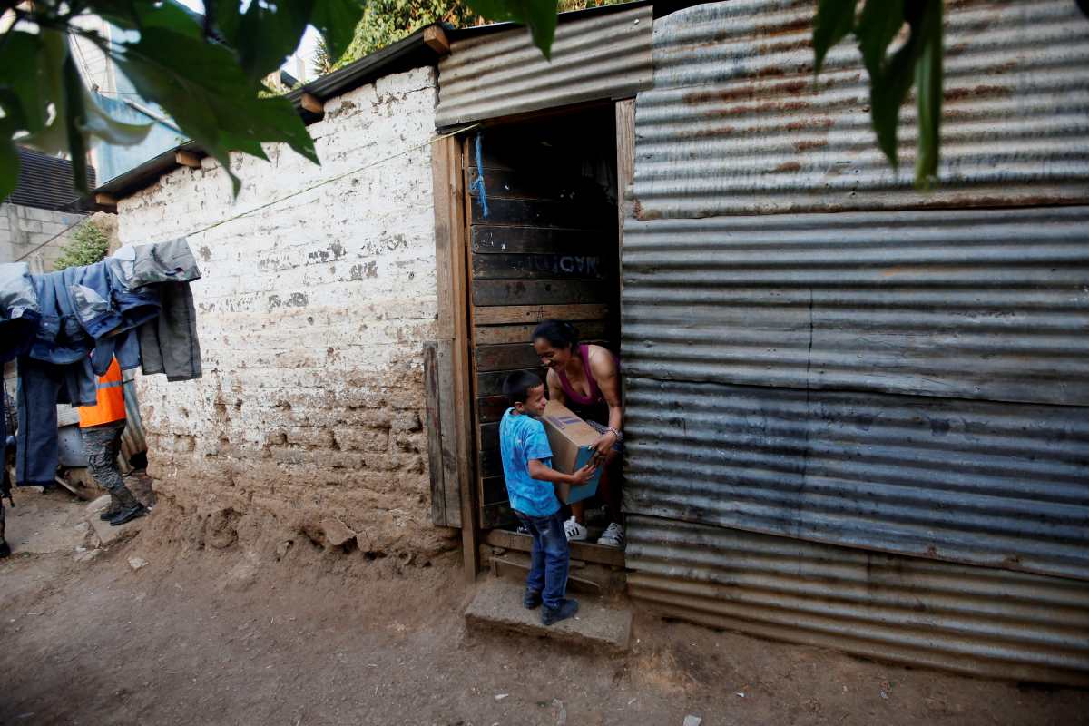Una mujer y su hijo cargan una caja con alimentos en un asentamiento de la periferia de la ciudad de Guatemala. El precio de los productos de la canasta básica comienza a afectar a las familias de más escasos recursos. (Foto Prensa Libre: EFE)
