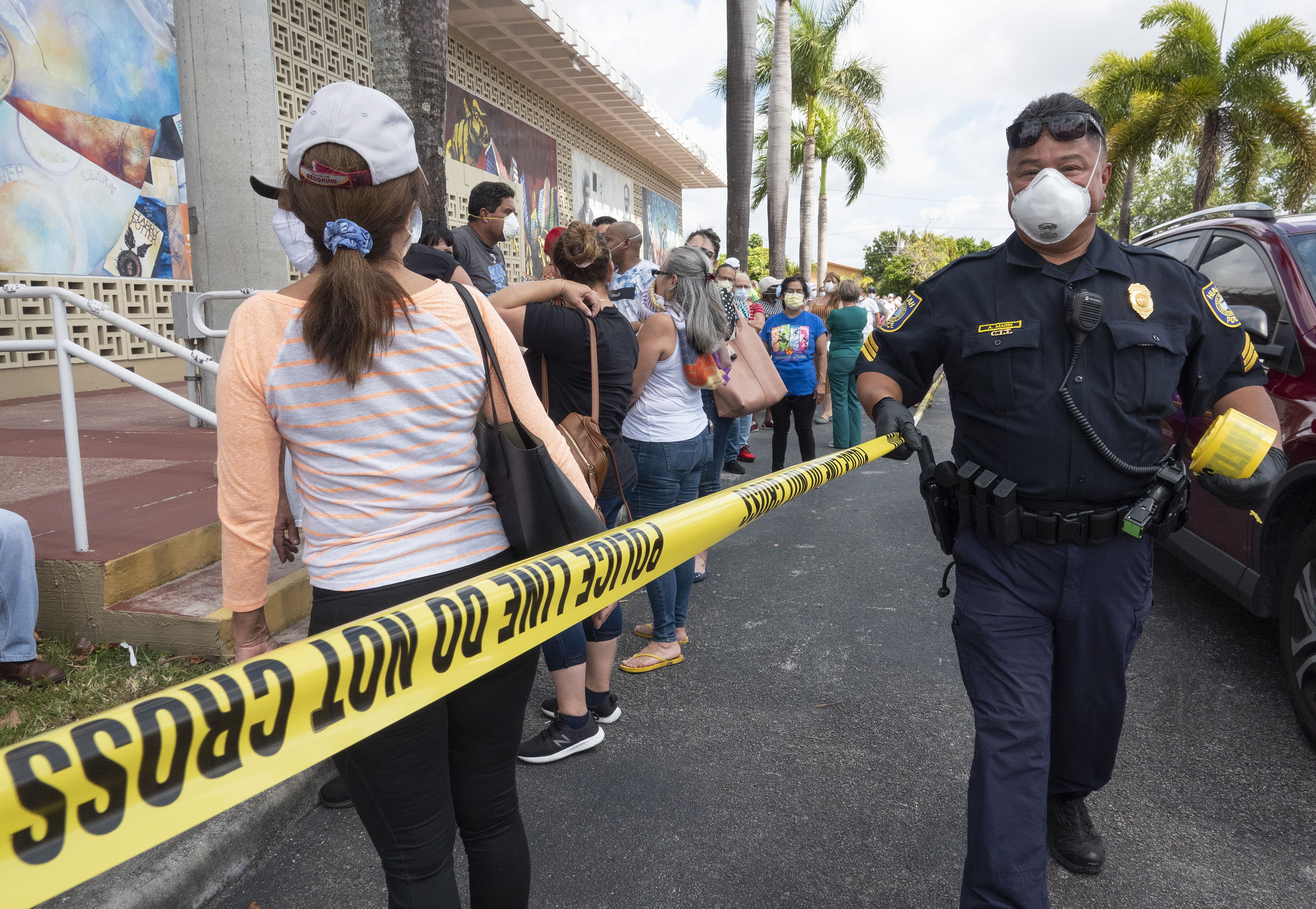 Hialeah (United States), 07/04/2020.- A Hialeah's police officer guards as people queue to deliver the printed Unemployment Benefits applications in the parking lot of Kennedy Library in Hialeah, Florida, USA, 07 April 2020. Hundreds of residents lined up hours before locations were scheduled to open Tuesday across Hialeah, to submit paper applications for unemployment benefits as the state attempts to address problems with its website amid the increased number of applicants during the widespread of the SARS-CoV-2 coronavirus which causes the Covid-19 disease. (Abierto, Estados Unidos) EFE/EPA/CRISTOBAL HERRERA
