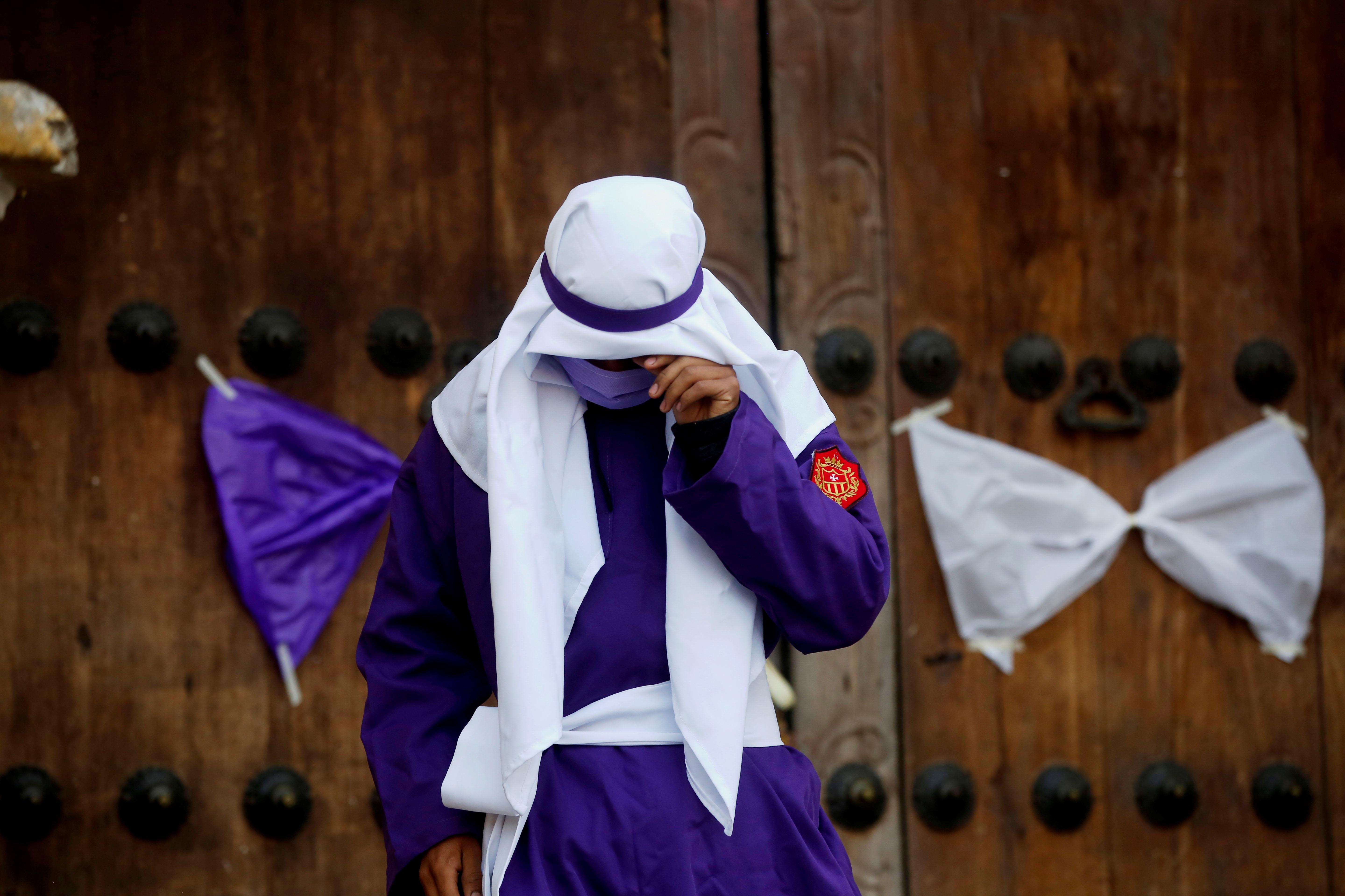 Un joven vestido de cucurucho llora mientras se aleja de la fachada de la iglesia La Merced en Antigua Guatemala el Viernes Santo del 2020, cuando se cancelaron las procesiones y en el país se mantenian vigentes muchas restricciones. (Foto Prensa Libre: EFE)