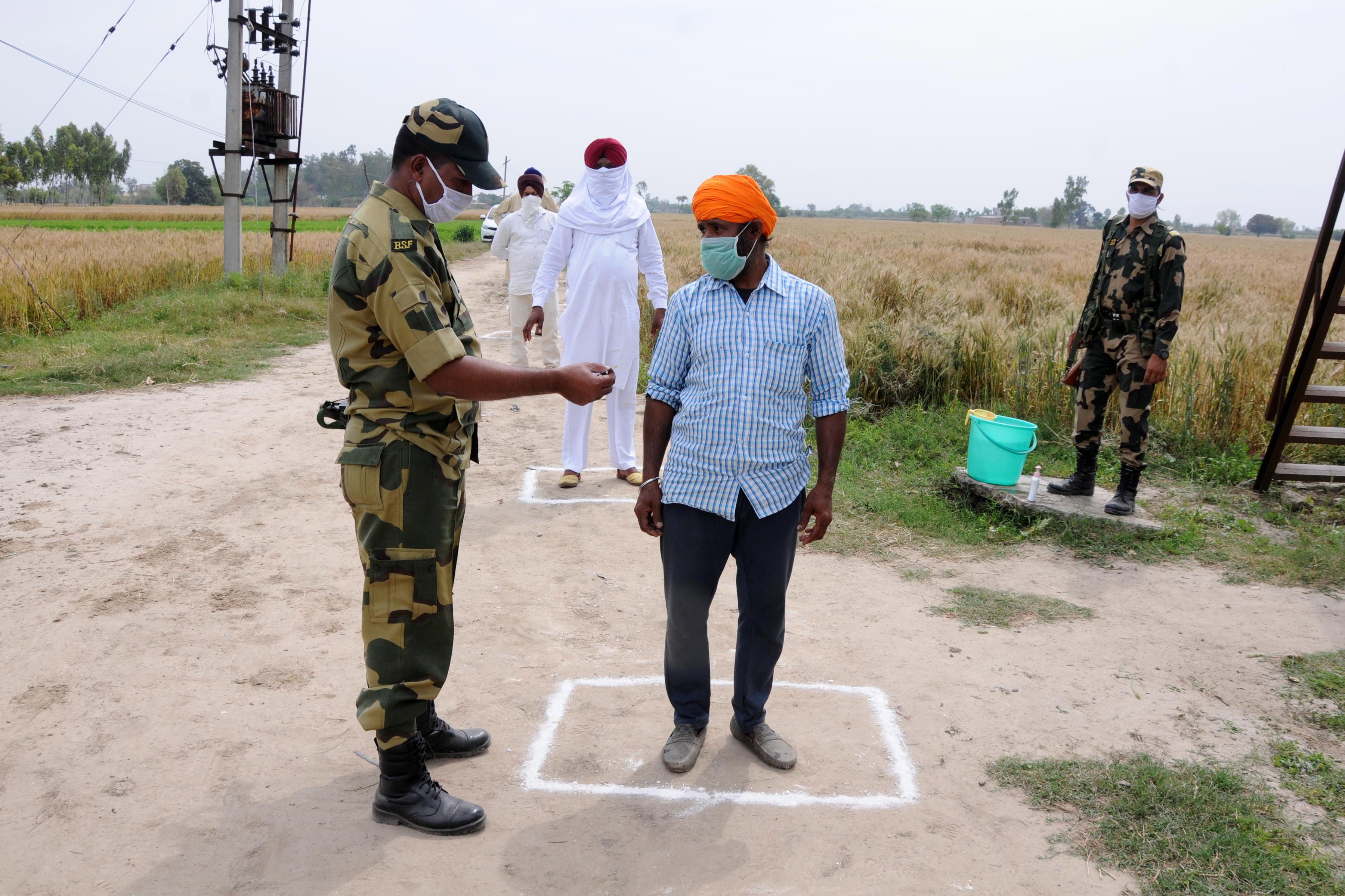 Un soldado en India revisa las tarjetas de identidad de los agricultores que cruzan una valla fronteriza. (Foto Prensa Libre: EFE)