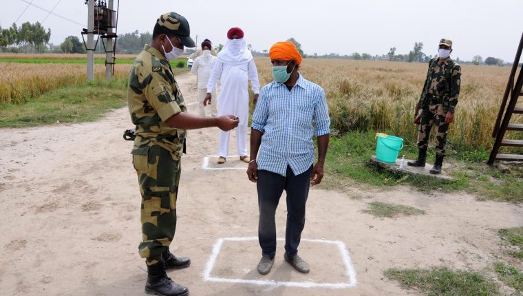 Un soldado en India revisa las tarjetas de identidad de los agricultores que cruzan una valla fronteriza. (Foto Prensa Libre: EFE)
