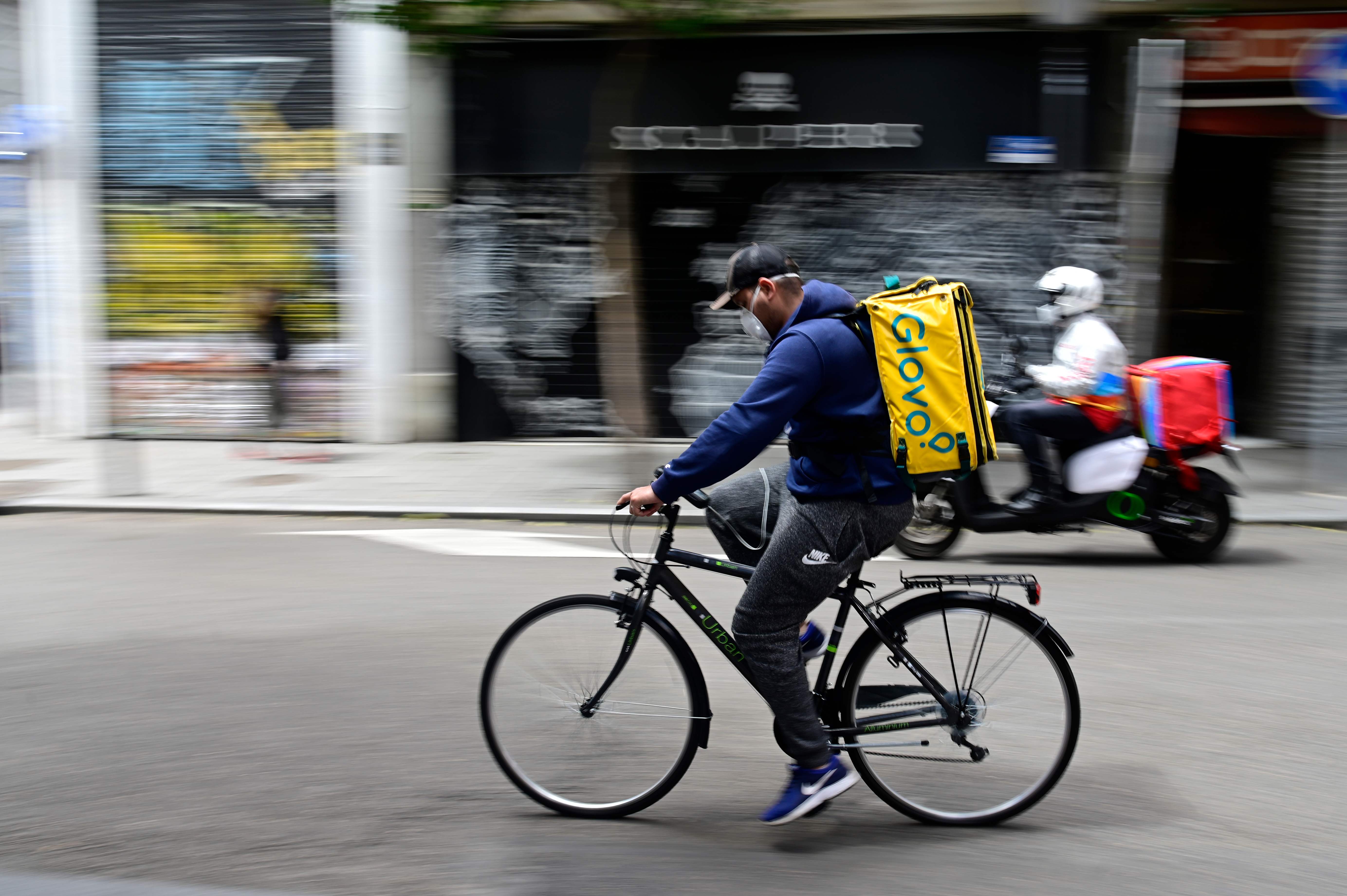 A cyclist working for the food delivery service Glovo rides in Madrid on April 30, 2020 during a national lockdown to prevent the spread of the COVID-19 disease. - Spain counted another 268 people who have died from the coronavirus, the lowest daily number since March 20 as the country prepares to ease its tough lockdown measures. (Photo by JAVIER SORIANO / AFP)