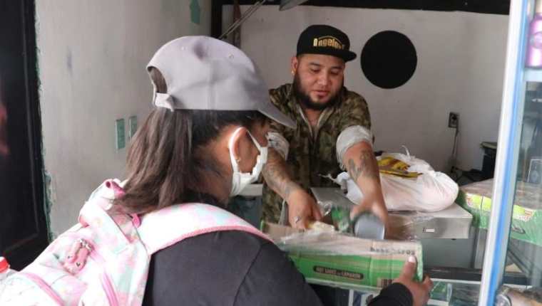 Arnold Estrada -de gorra- atiende a una persona que lleva ayuda para personas afectadas por la crisis del coronavirus. (Foto Prensa Libre: Raúl Juárez).