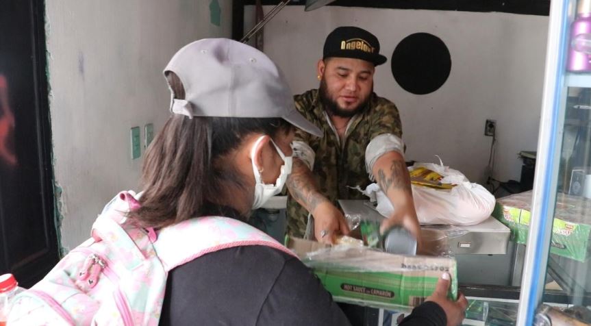 Arnold Estrada -de gorra- atiende a una persona que lleva ayuda para personas afectadas por la crisis del coronavirus. (Foto Prensa Libre: Raúl Juárez).