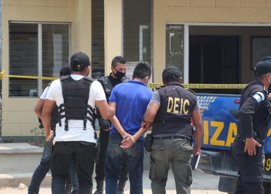Autoridades trasladan a uno de los capturados señalados del asalto a un banco en Poptún, Petén. (Foto Prensa Libre: PNC). 