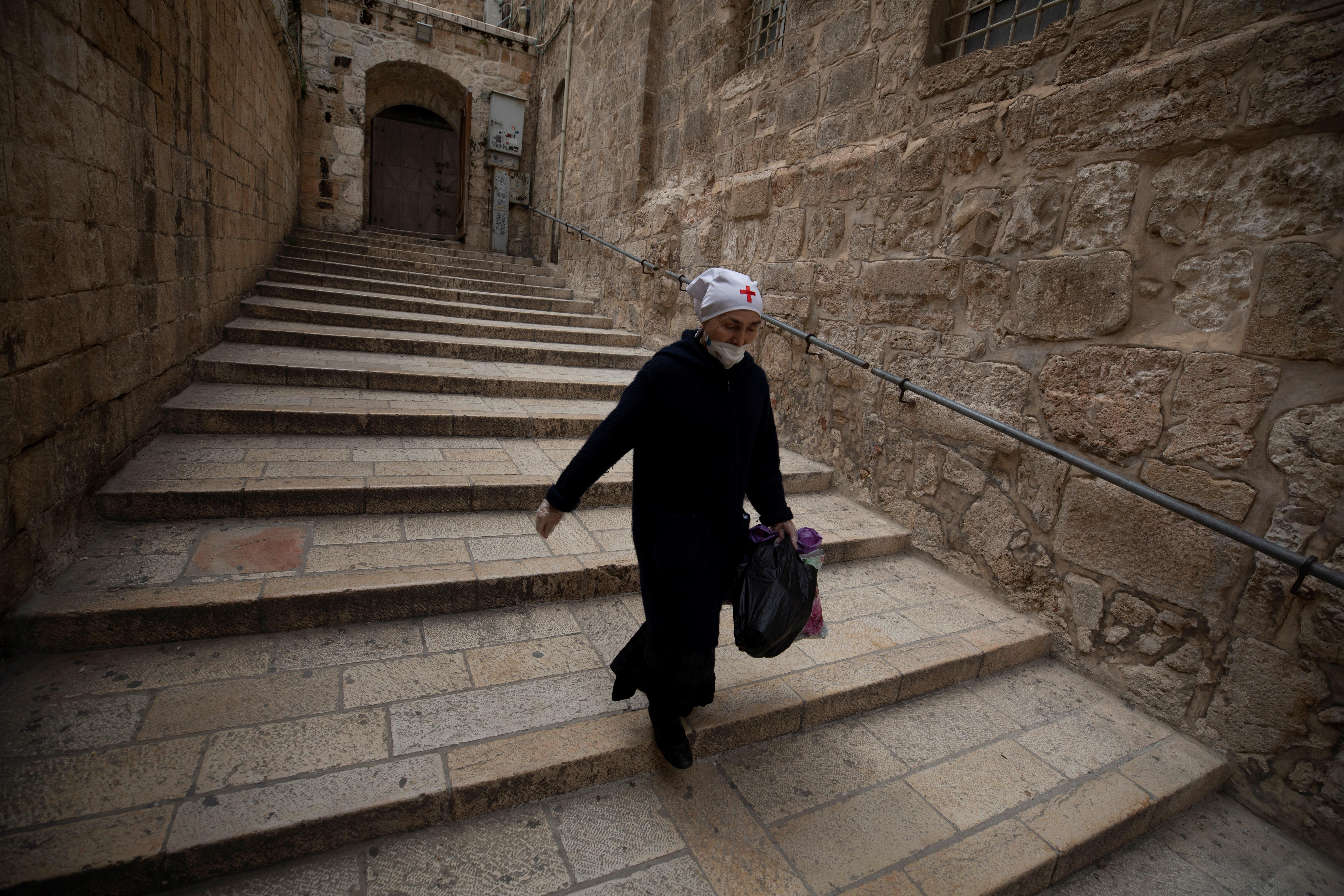 Una monja ataviada con una mascarilla facial camina dentro de la Iglesia del Santo Sepulcro en Jerusalén, Israel, en una Semana Santa inusual por el confinamiento. (Foto Prensa Libre: EFE)