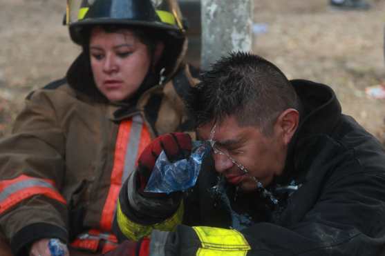 Los bomberos rociaron agua en sus rostros para limpiarlos después de haber subido hasta las colonias. Foto Prensa Libre: Óscar Rivas