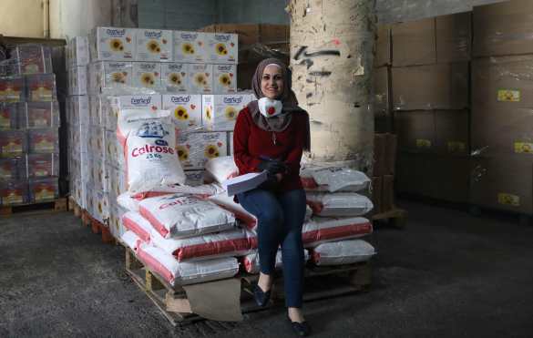  El palestino Iman Abu Areesh, de 32 años, coordinador del comité de Emergencia y Ayuda de la oficina del gobernador de Hebrón, posa para una foto junto a montones de ayuda humanitaria, en la ciudad ocupada de Cisjordania el 22 de abril de 2020 durante la pandemia de coronavirus COVID-19. Foto Prensa Libre: AFP