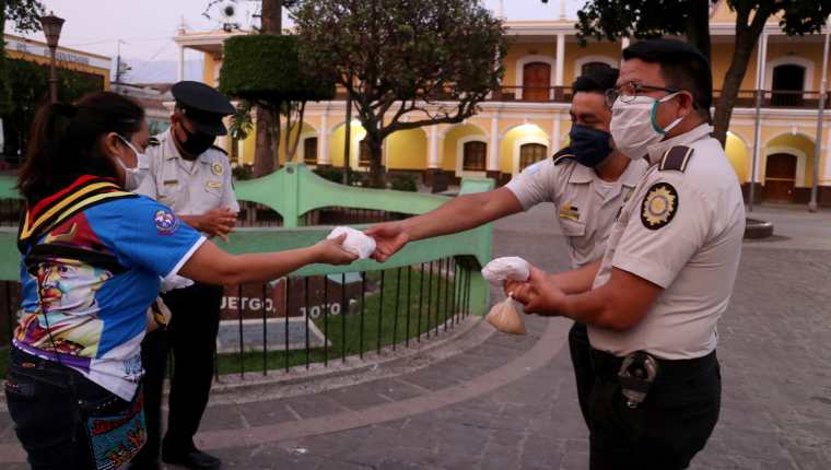 Una scout entrega panes a agentes de la Policía Nacional Civil en Huehuetenango durante una jornada de solidaridad con las fuerzas de seguridad. (Foto Prensa Libre. Mike Castillo)