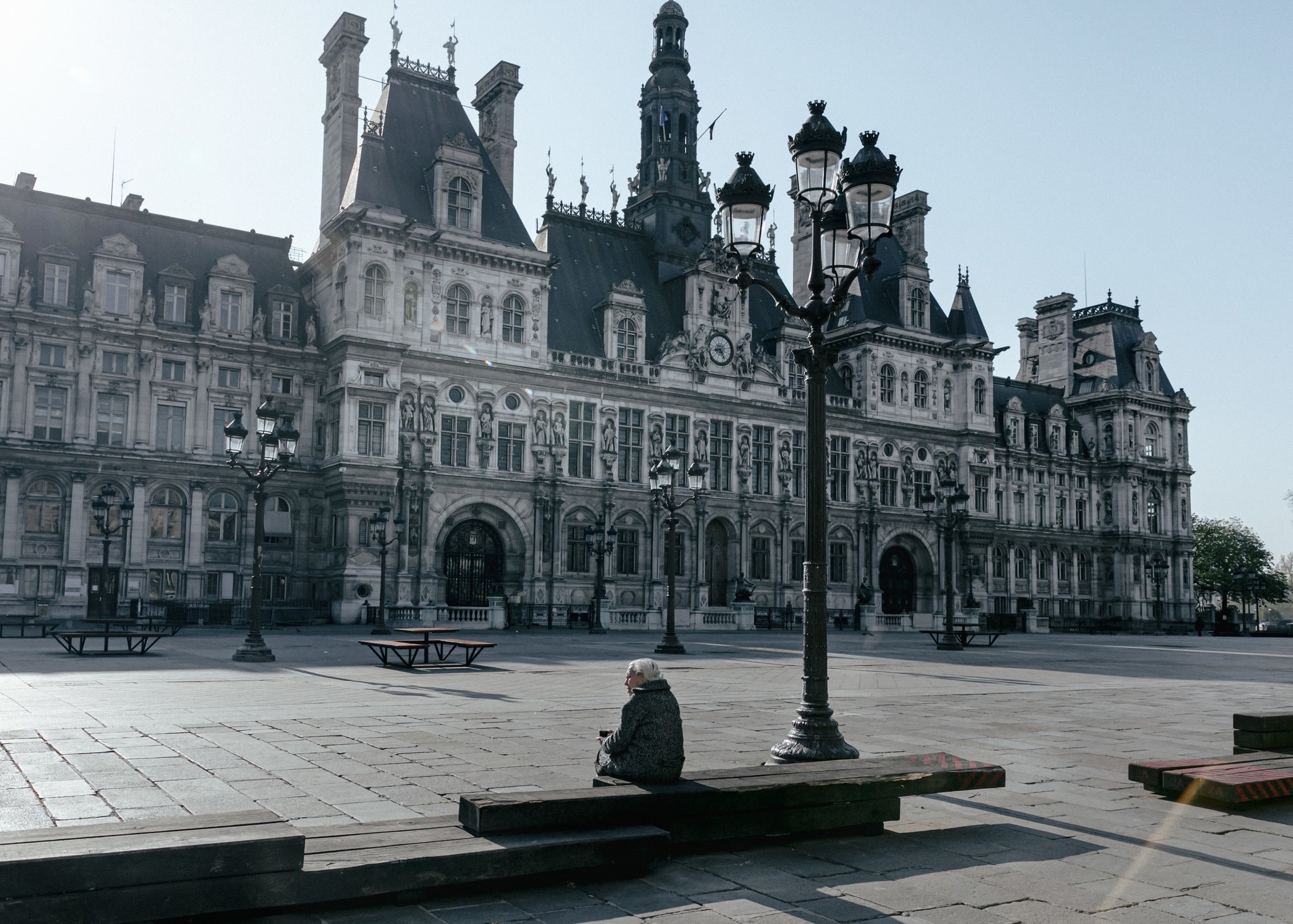 Una mujer está sentada sola en la explanada del Ayuntamiento de París el 9 de abril de 2020. (Andrea Mantovani/The New York Times)
