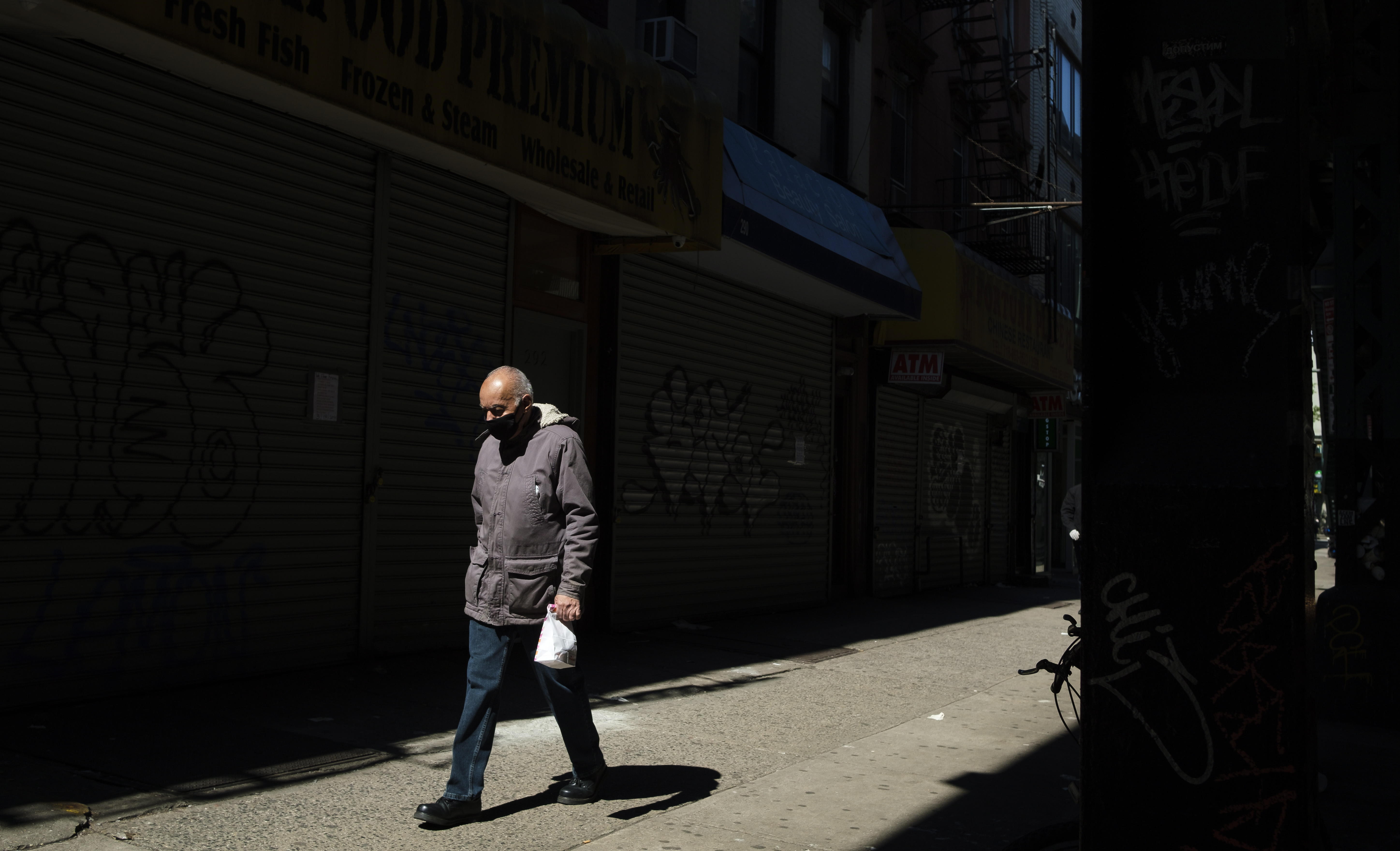 Un hombre camina por una calle con muchos negocios cerrados en Brooklyn, Nueva York. (Foto Prensa Libre: EFE)
