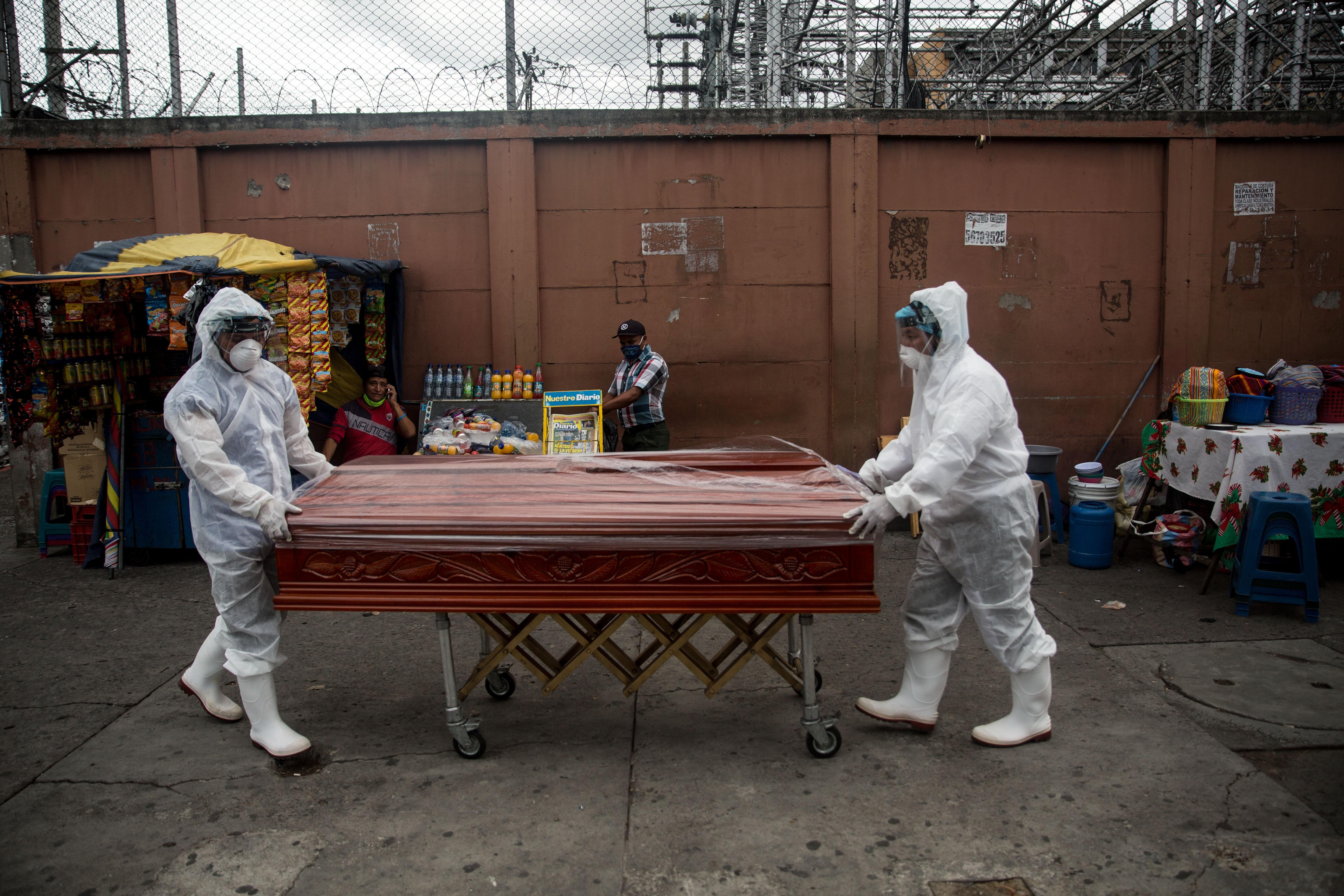 Trabajadores de una funeraria transportan el féretro de una mujer fallecida por coronavirus, desde el Hospital General San Juan de Dios que será destinado a casos críticos. (Foto Prensa Libre: EFE)