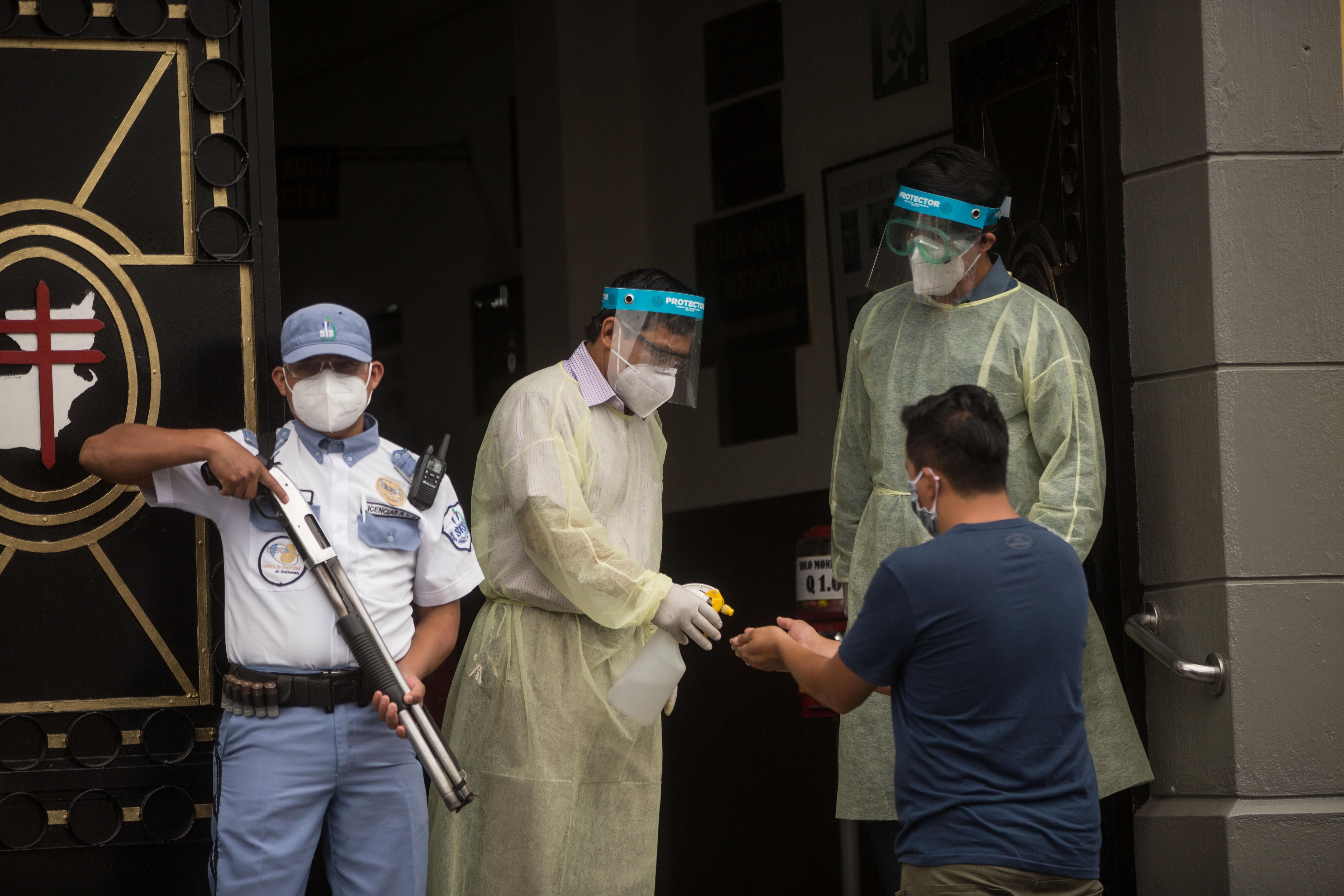 Personal médico reparte gel desinfectante a pacientes que entran a consulta en el Hospital General San Juan de Dios. (Foto Prensa Libre: EFE)