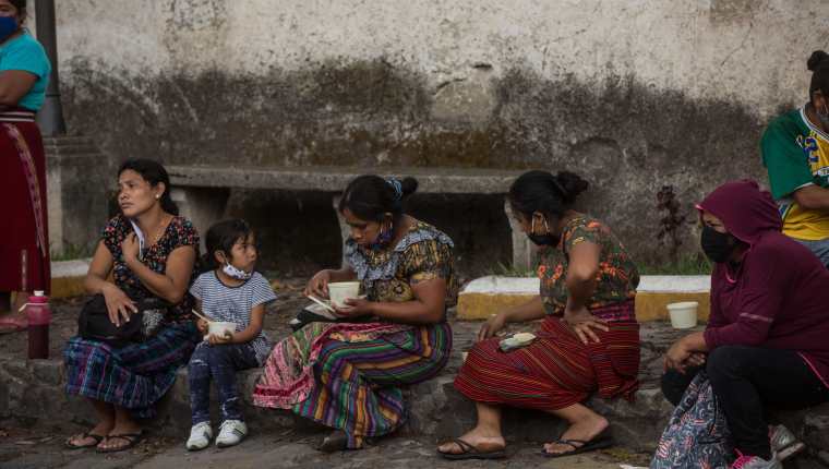 Fotografía del 29 de mayo de 2020 que muestra unas personas después de recibir almuerzos gratuitos de la organización Banderas Blancas Sacatepéquez, en el centro cultural Casa del Río en Antigua (Guatemala). (Foto Prensa Libre: EFE)