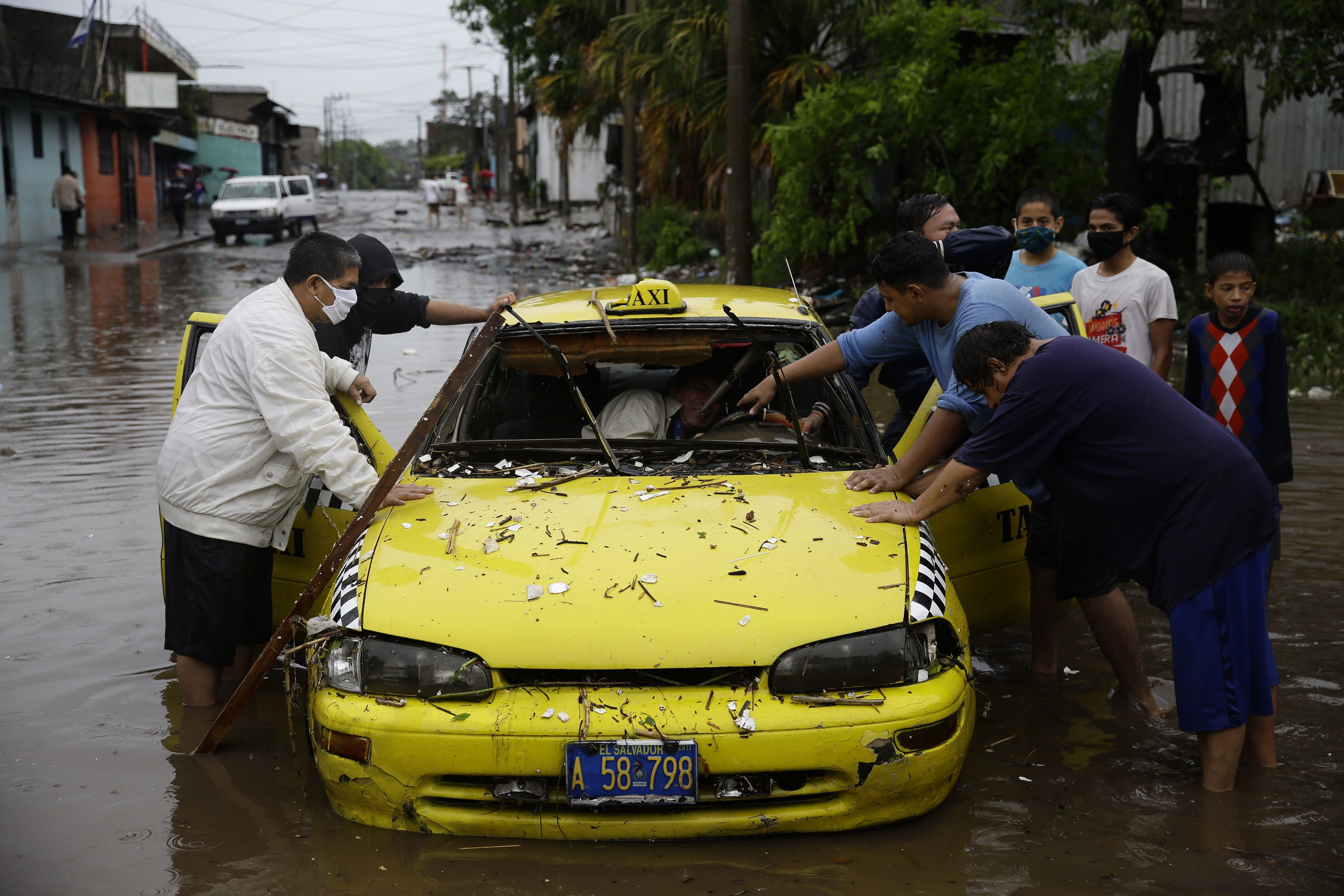Residentes intentan empujar un taxi este domingo en una inundada calle de San Salvador (El Salvador). por las intensas lluvias generadas por la tormenta Amanda a su paso por la región. (Foto Prensa Libre: EFE)