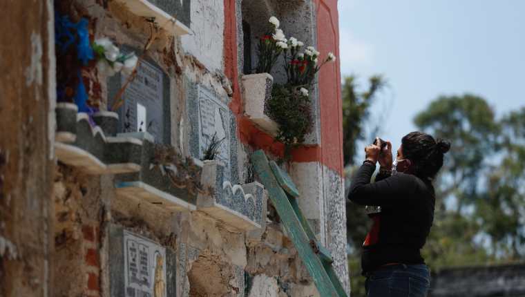 Uno de los colaboradores toma la foto de una tumba para mostrarla a uno de los deudos, que espera afuera del cementerio. (Foto Prensa Libre: Esbin García)