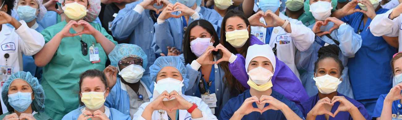Enfermeros y encargados de la salud realizan con sus manos un gesto de corazón en celebración por el Día Internacional de la enfermera en las afueras del hospital Mt. Sinai Queen, en Nueva York. Fotografía Prensa Libre: Angela Weiss / AFP. 