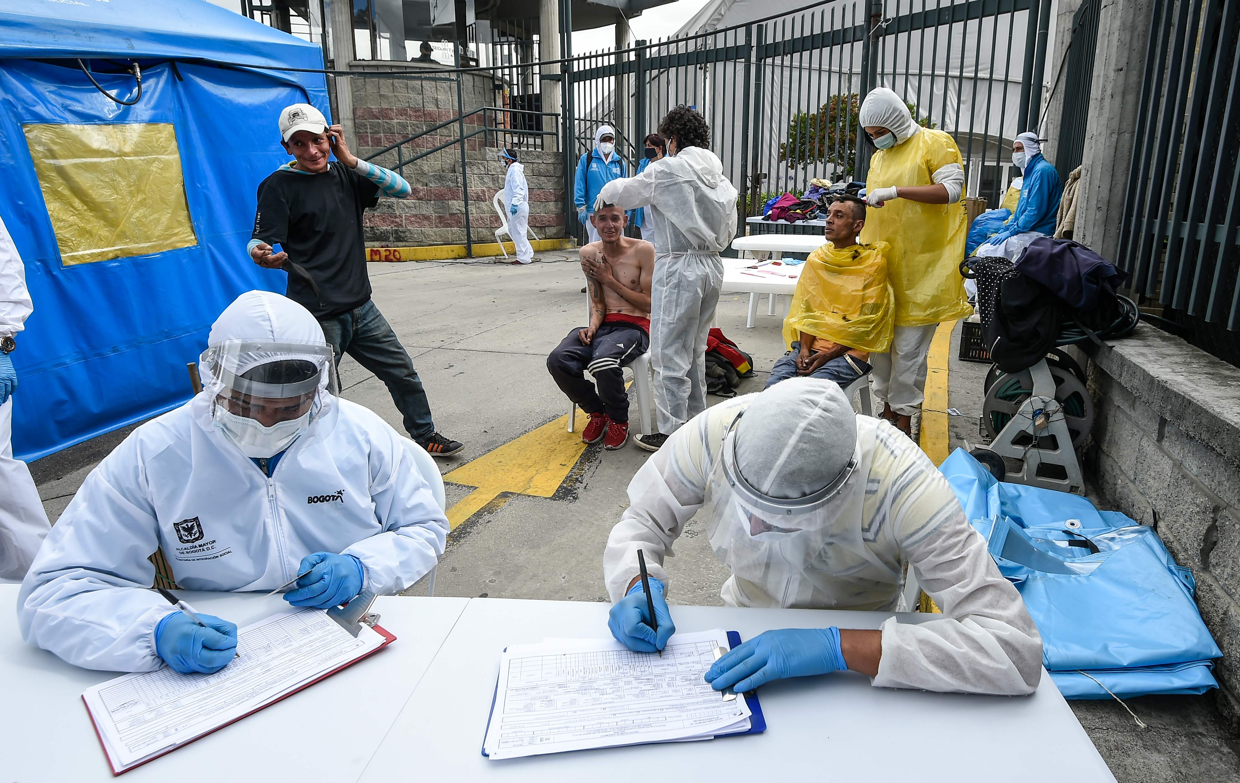 Trabajadores que ayudan a personas sin hogar usan equipo de protección personal contra la propagación del nuevo coronavirus, este 20 de mayo de 2020 en Bogotá, Colombia. (Foto Prensa Libre: AFP)