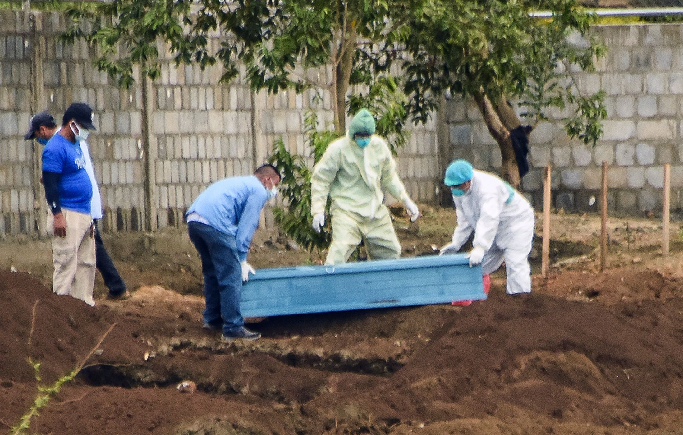 Trabajadores de Salud con trajes protectores entierran a una víctima de covid-19 en el cementerio de Managua. (Foto Prensa Libre: AFP)