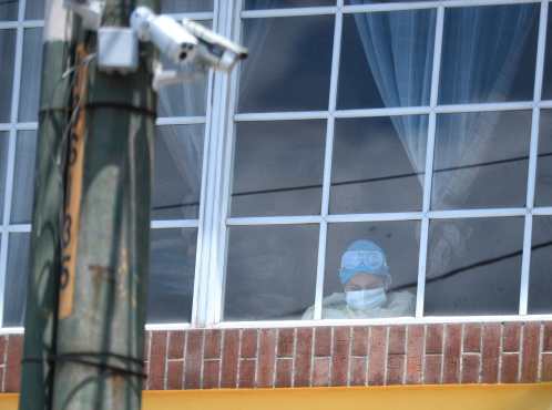 Una persona que labora en un hospital temporal del Instituto Guatemalteco de Seguridad Social toma un breve descanso y se acerca a una de las ventanas del lugar. Foto Prensa Libre: Carlos Hernández