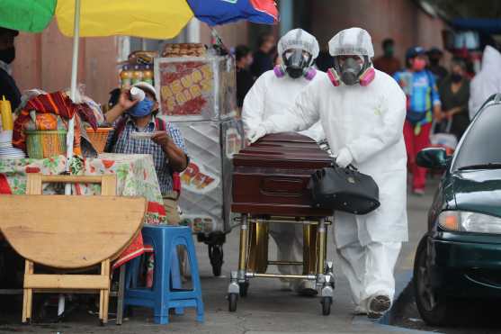 Quienes ingieren alimentos afuera del hospital San Juan de Dios pueden observar a los empleados de las funerarias pasar con los difuntos. Foto Prensa Libre: Érick Ávila 