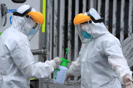 Después del traslado de una persona los paramédicos de una ambulancia se desinfectan antes de regresar al vehículo. Foto Prensa Libre: Juan Diego González