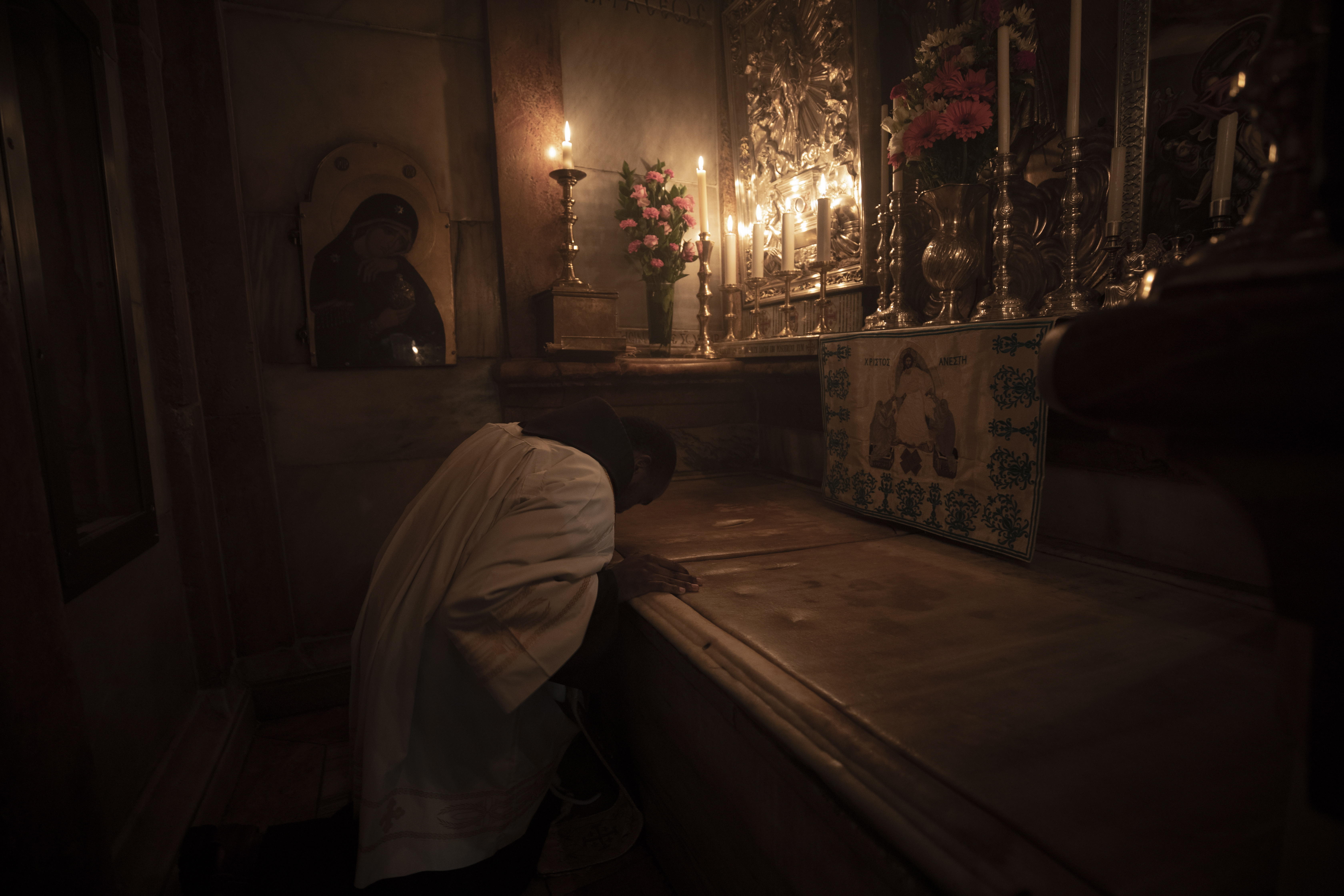 Un monje franciscano reza en la losa de mármol que cubre la Tumba de Jesús, en la Basílica del Santo Sepulcro, que abre sus puertas al público este domingo. (Foto Prensa Libre: EFE)