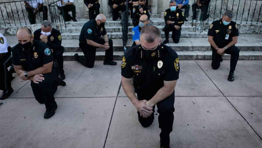 Oficiales de policía de EE. UU. se arrodillaron durante una manifestación en Coral Gables, Florida, en respuesta a la reciente muerte de George Floyd. (Foto Prensa Libre: AFP)