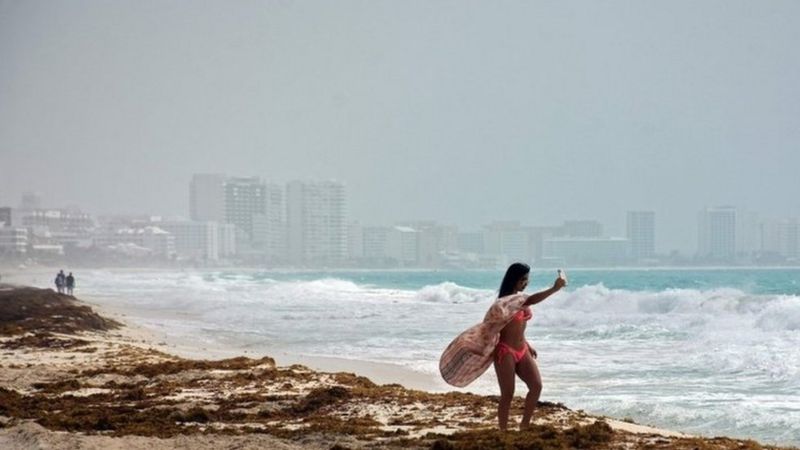 Algunas personas aprovechan la llegada del fenómeno para tomarse fotos en Cancún, México. (Foto Prensa Libre: AFP)