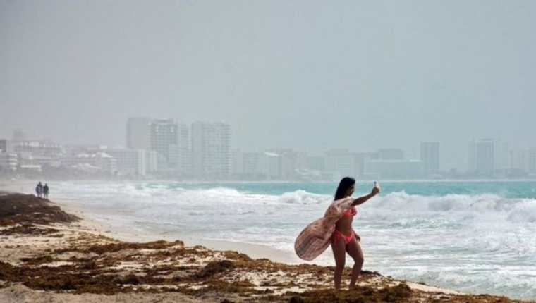 Algunas personas aprovechan la llegada del fenómeno para tomarse fotos en Cancún, México. AFP