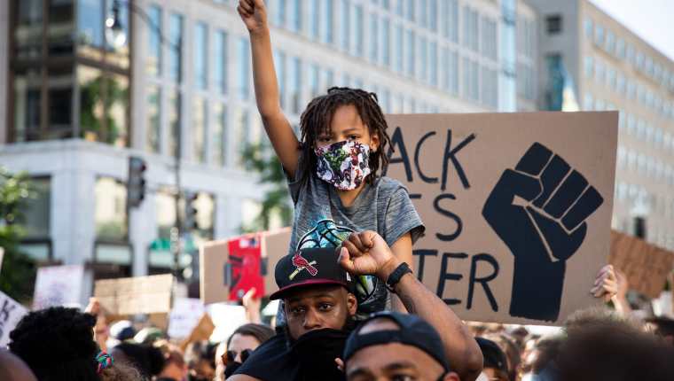 Un hombre y un niño participan en las protestas por la muerte de George Floyd cerca de la Casa Blanca. Foto Prensa Libre