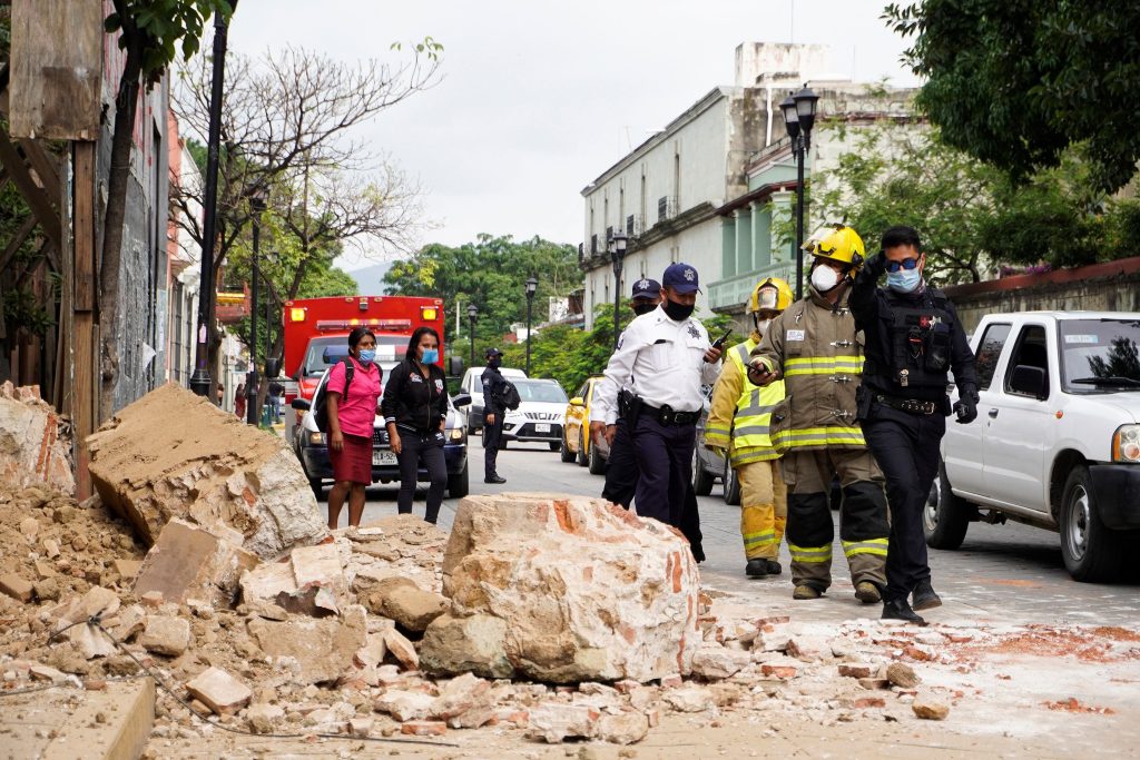 Miembros de la policía y de los bomberos observan los daños causados en una barda derrumbada este martes en Oaxaca. (Foto Prensa Libre: EFE)