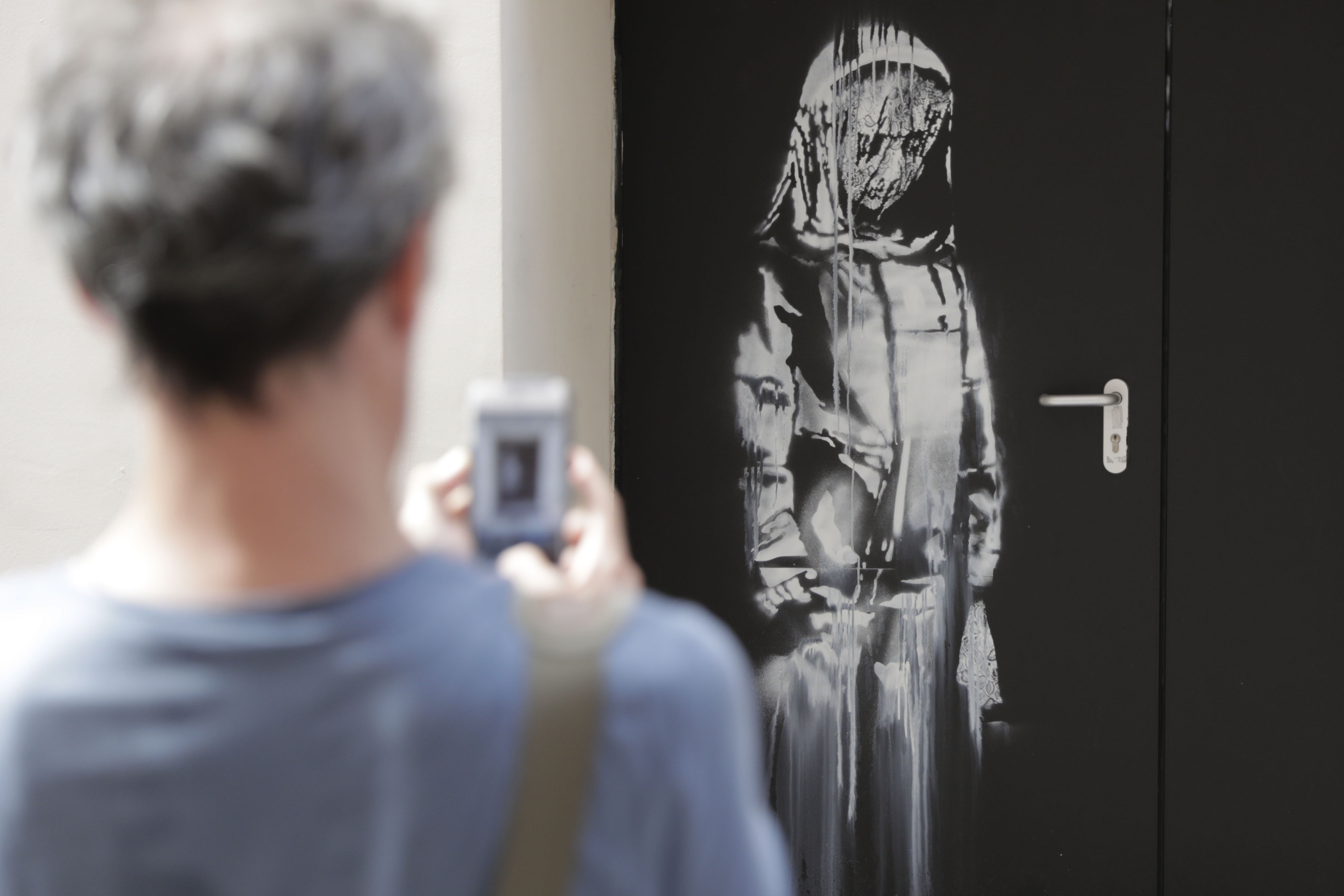 En esta foto de archivo tomada el 25 de junio de 2018, un hombre toma una fotografía de una obra de arte del artista callejero Banksy en París en una calle lateral a la sala de conciertos Bataclan donde un ataque terrorista mató a 90 personas el 13 de noviembre de 2015. (Foto Prensa Libre: AFP).