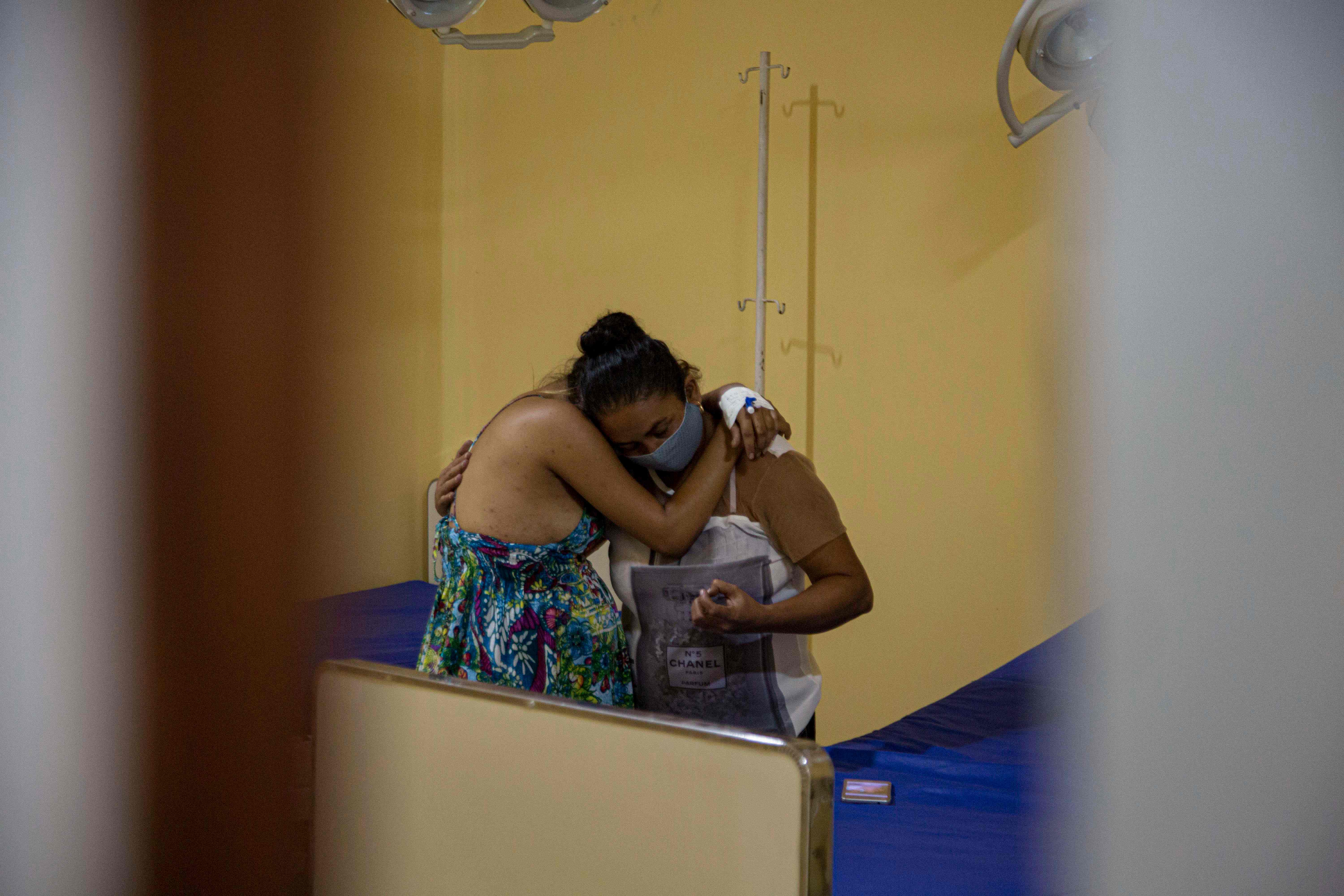 Una paciente con covid-19 abraza a una mujer en labor de parto en Melgaco, estado de Para, Brasil. (Foto Prensa Libre: AFP)