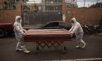 Empleados de una funeraria utilizan traje de bioseguridad para transportar el cuerpo de una de las victimas mortales de covid - 19. Fotografía: Prensa Libre. 
