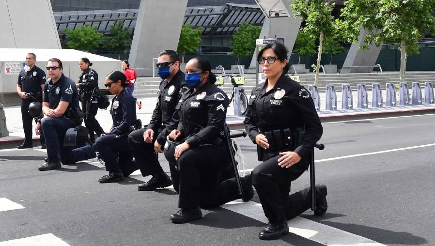 Los oficiales del Departamento de Policía de Los Ángeles, EE. UU., se arrodillan durante una manifestación en memoria de George Floyd. (Foto Prensa Libre: AFP)
