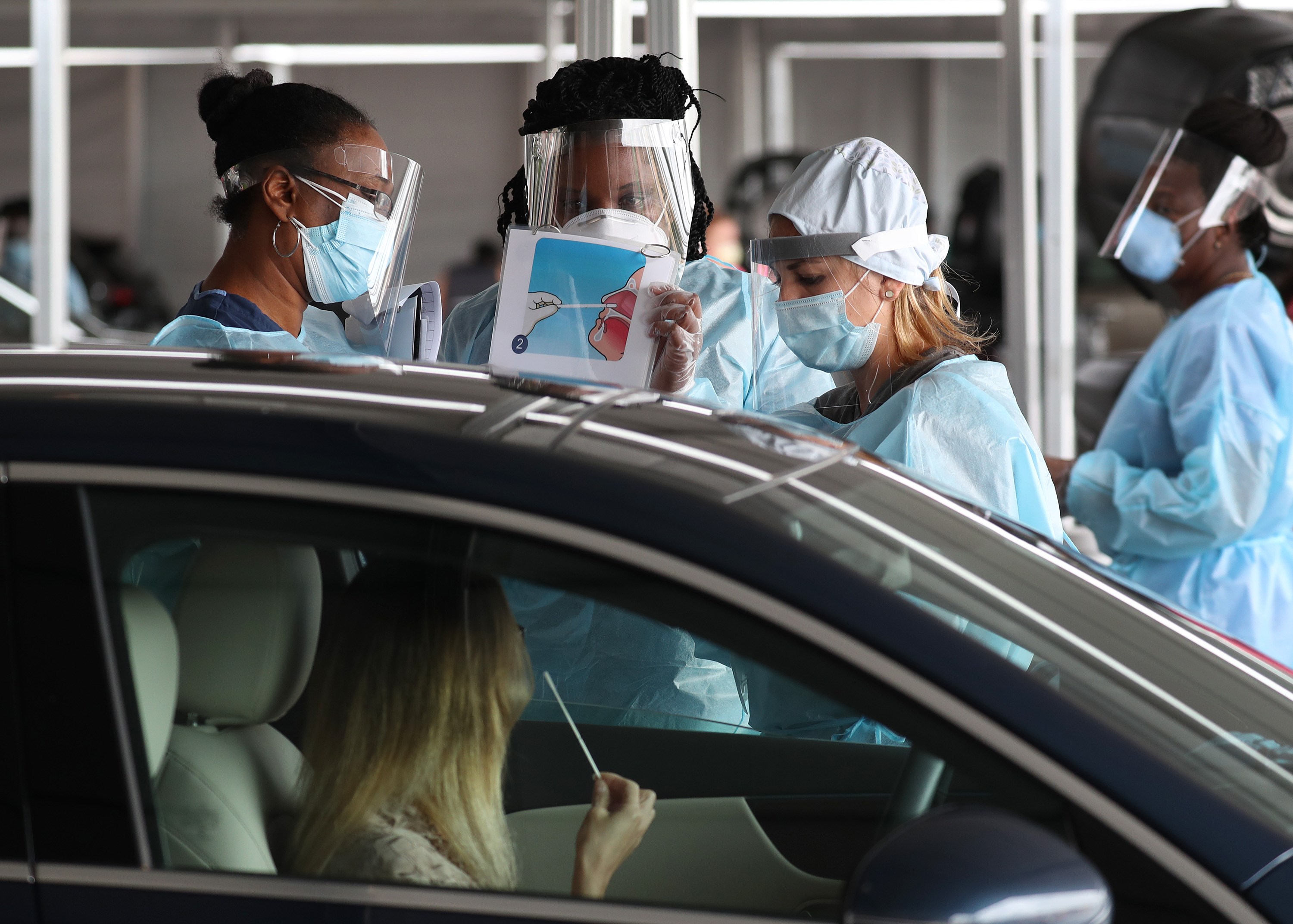MIAMI, FLORIDA - JULY 23: A health care worker uses a picture to show a person how to use a nasal swab for a self administered test at the new federally funded COVID-19 testing site at the Miami-Dade County Auditorium on July 23, 2020 in Miami, Florida. U.S. Surgeon Jerome M. Adams visited the site, as the state of Florida experiences a spike in coronavirus cases, to encourage people to wear a mask and take other precautions to fight the pandemic.   Joe Raedle/Getty Images/AFP
== FOR NEWSPAPERS, INTERNET, TELCOS & TELEVISION USE ONLY ==