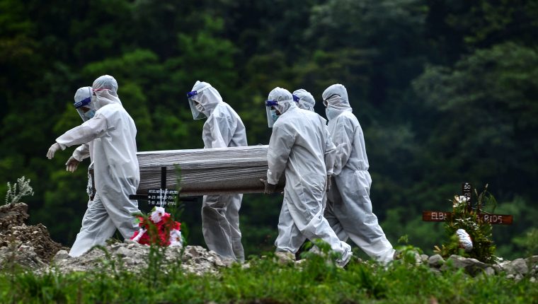 Men in protective suits carry the coffin of an alleged victim of the new coronavirus at the Parque Memorial Jardin de los Angeles cemetery, 14 km north of Tegucigalpa, on June 21, 2020. - Honduras is overwhelmed by deaths caused by COVID-19 and the large number of people infected that are admitted every day in different hospitals across the country. (Photo by ORLANDO SIERRA / AFP)
