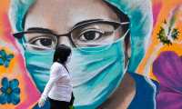 A woman walks past a coronavirus-related mural painted by urban artist Alejandro Bautista Torres, 38, aka Kato, in Mexico City, on July 15, 2020, during the novel COVID-19 pandemic. (Photo by PEDRO PARDO / AFP)