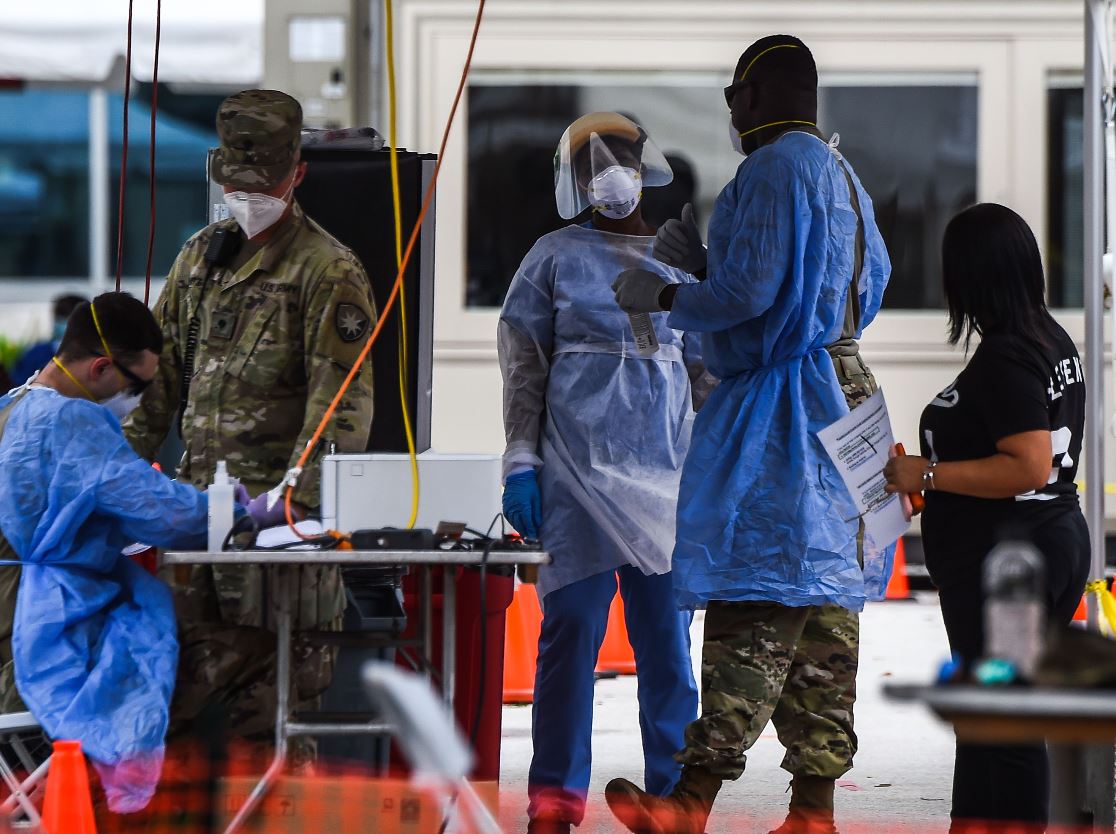 Un integrante de la Guardia Nacional habla con una persona en un automóvil que espera una prueba covid-19 en un sitio de prueba de coronavirus en Miami Beach, Florida. (Foto Prensa Libre: AFP)