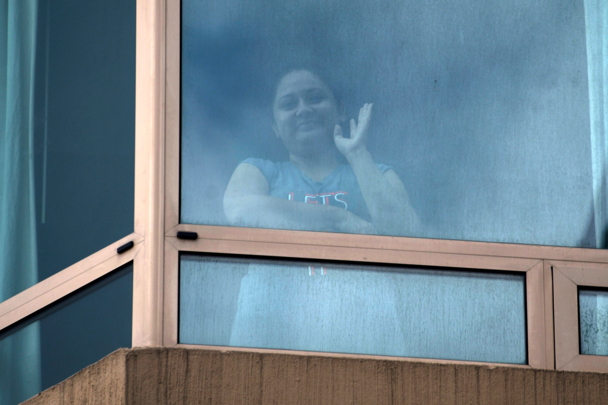 Desde la ventana de la habitación donde se recupera de coronavirus, Yoselin Solórzano saluda a su novio, Miguel Ángel Taque. (Foto Prensa Libre: AFP)