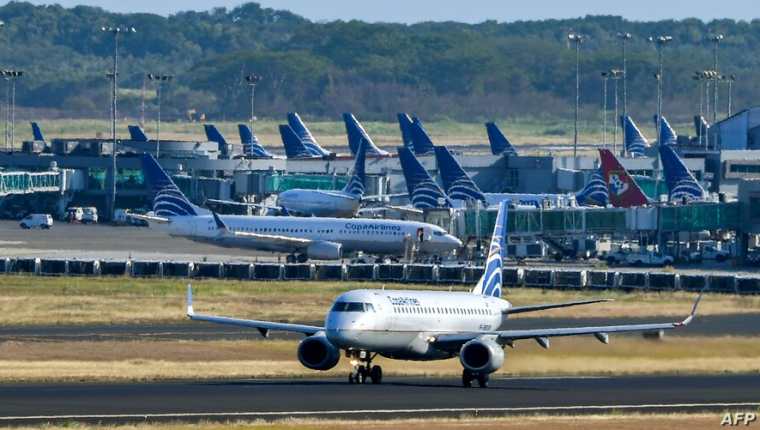 Un avión de Copa Airlines es visto en una pista mientras otro aterriza del aeropuerto internacional de Tocumen, el 22 de marzo de 2020.  (Foto Prensa Libre: La Voz de América)
