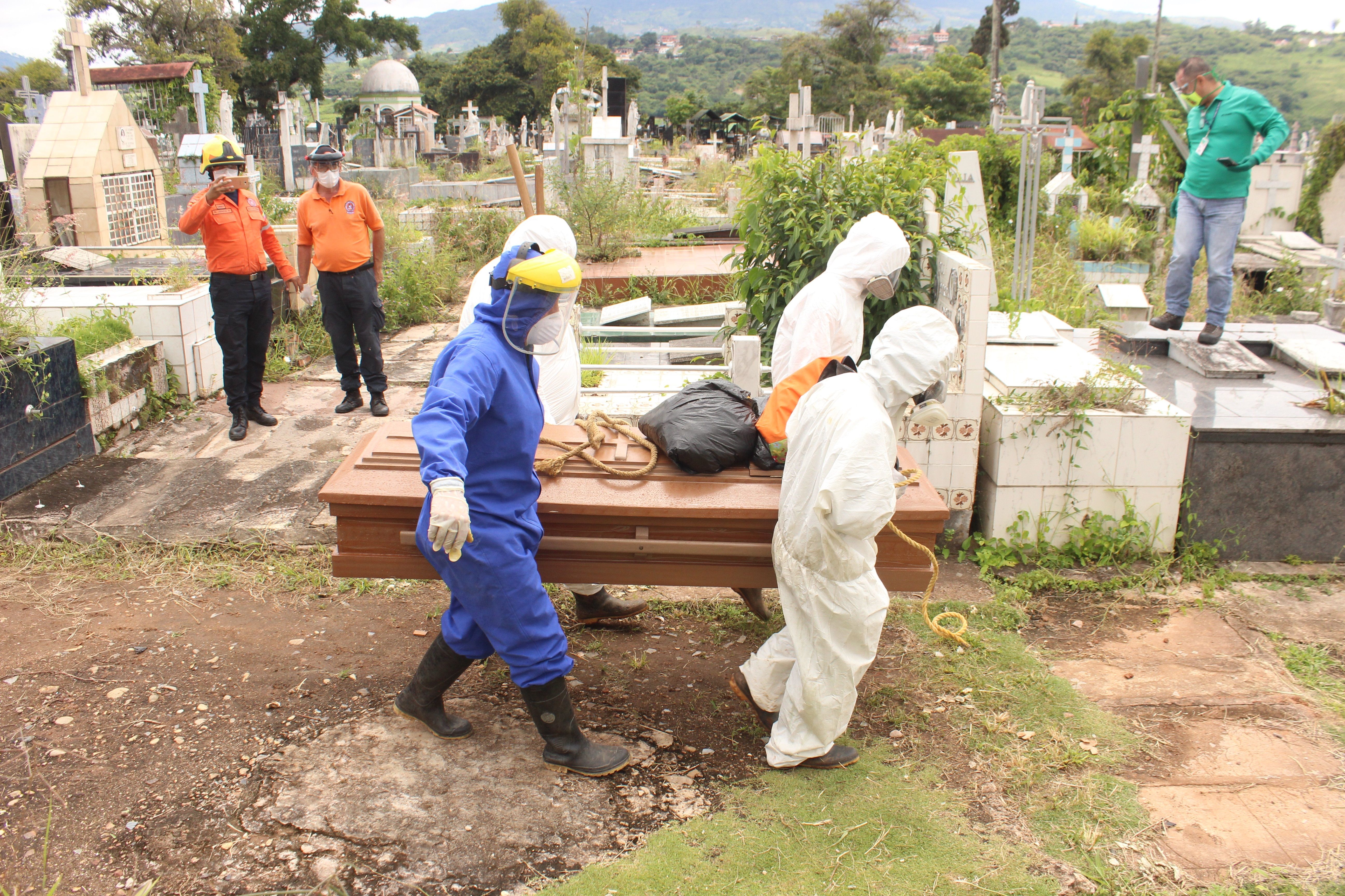 Trabajadores gubernamentales proceden a enterrar un féretro con una víctima de covid-19 en el cementerio de San Cristóbal, estado Táchira. (Foto Prensa Libre: EFE)